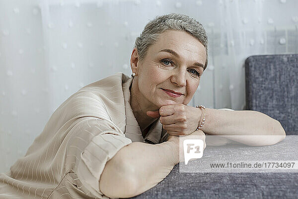 Portrait of mature woman with short grey hair leaning on couch