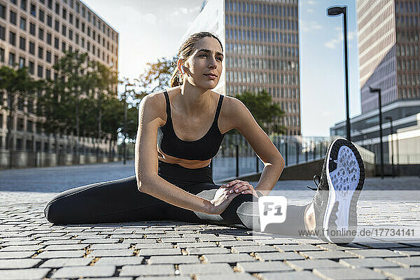 Flexible junge Frau trainiert auf dem Fußweg