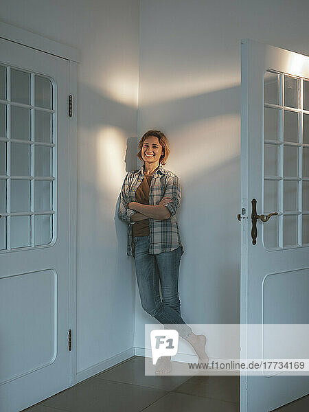 Happy woman leaning on wall by door