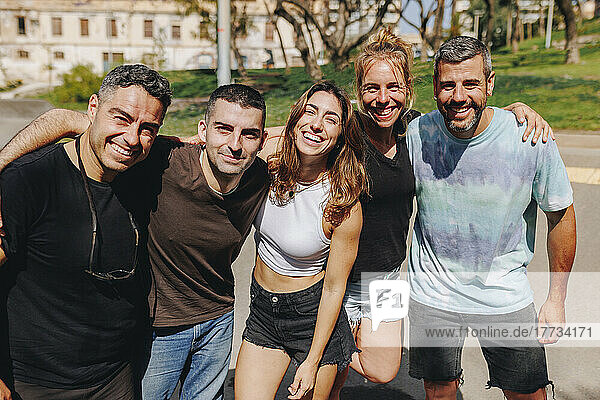 Smiling women and men at skateboard park on sunny day