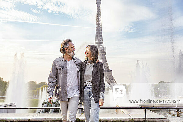 Smiling mature man and woman looking at each other in front of Eiffel Tower  Paris  France