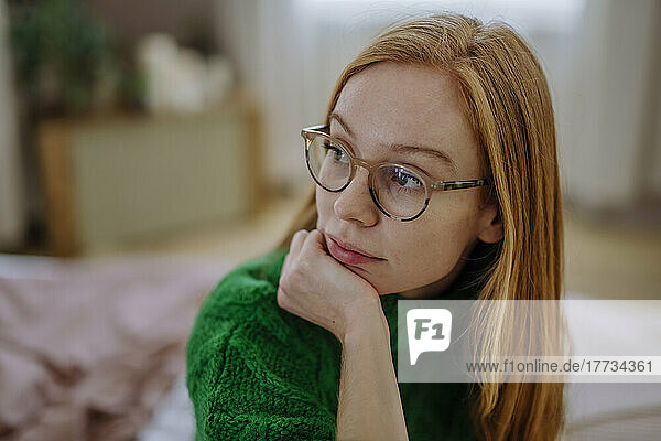 Thoughtful woman with hand on chin at home