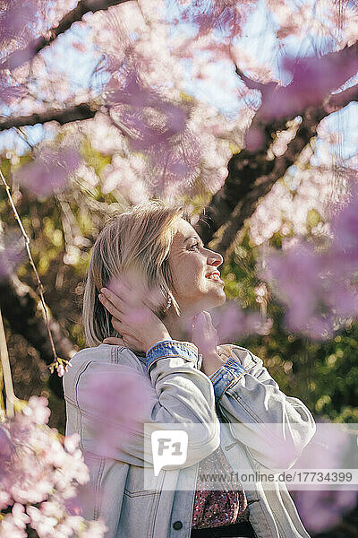 Smiling blond woman standing in garden on sunny day