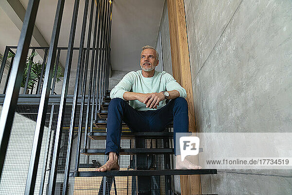 Nachdenklicher Mann sitzt zu Hause auf der Treppe