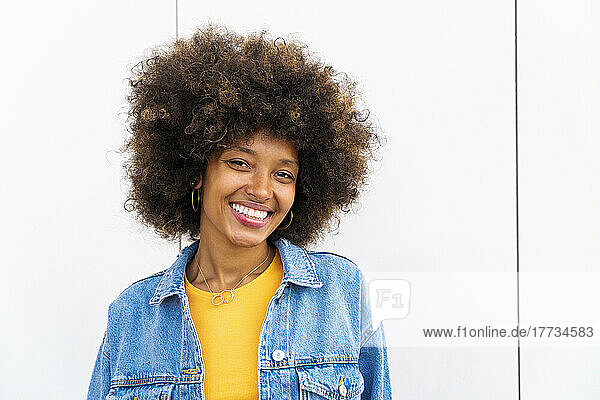 Happy beautiful woman with Afro hairstyle in front of wall