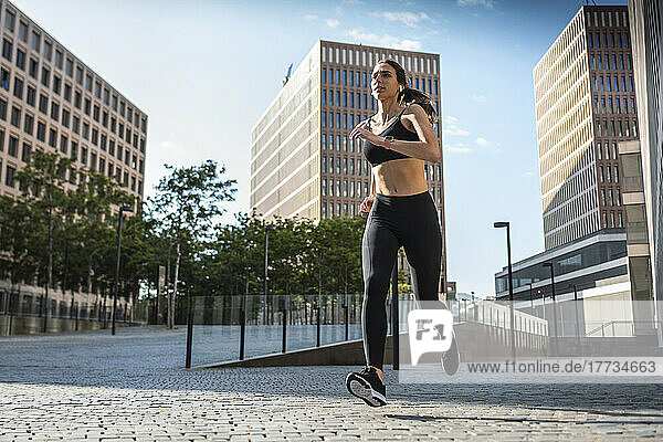 Young woman jogging in city on sunny day