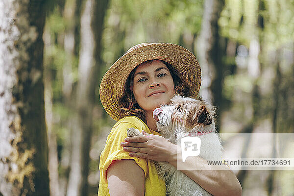 Woman carrying dog in forest