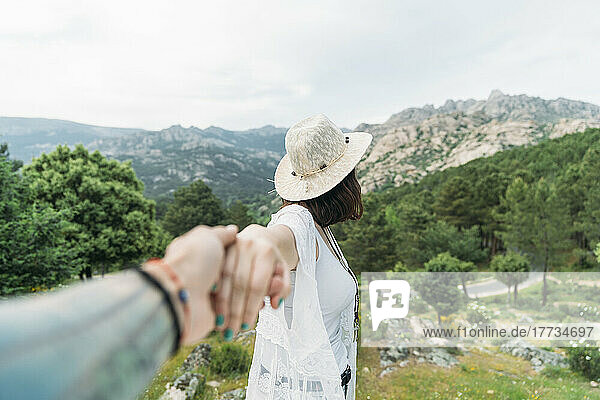 Man holding girlfriend's hand in front of mountain range