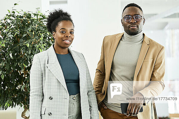 Smiling young businesswoman standing with colleague in modern office