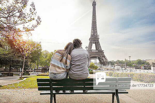 Mature couple sitting together on bench in front of Eiffel tower  Paris  France