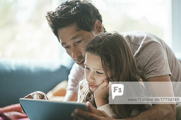 Nettes Mädchen mit Vater  der zu Hause einen Tablet-PC benutzt