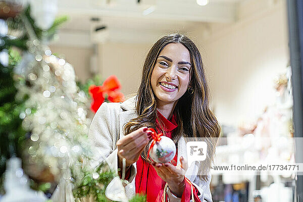 Happy young woman holding decoration in shop