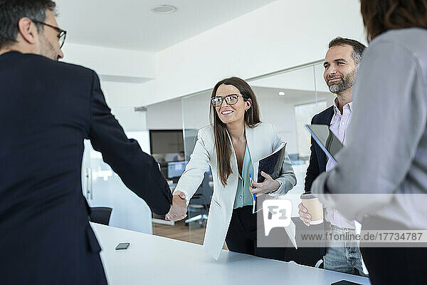 Businesswoman shaking hands with colleague in office