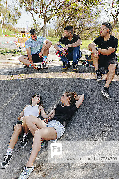 Friends taking break and relaxing at skateboard park