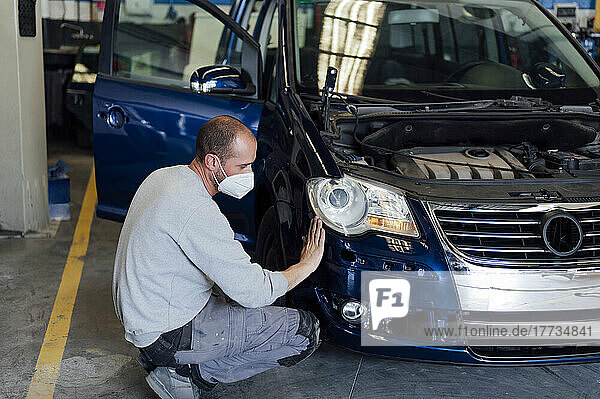 Auto mechanic analyzing car bumper in workshop