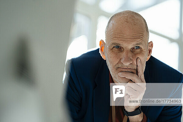 Thoughtful businessman with hand on chin in office