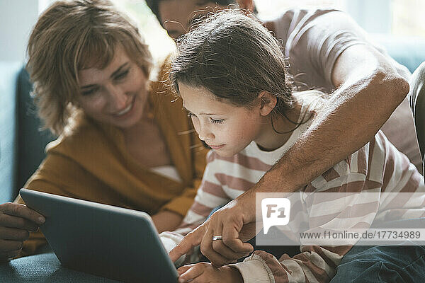 Parents with daughter using tablet PC at home
