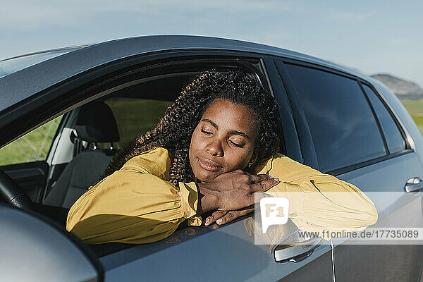 Woman with eyes closed sitting in car on sunny day