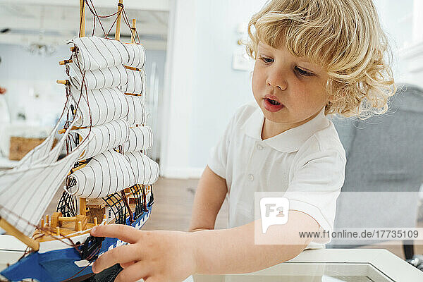 Cute boy playing with toy boat at home