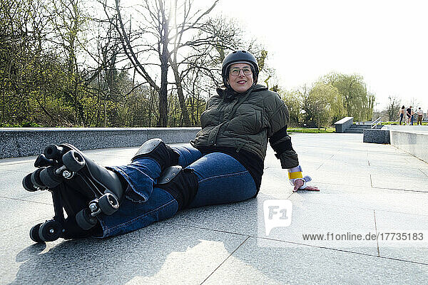 Woman resting on footpath with roller skates in park