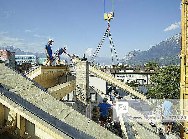Blue-collar workers at construction site standing on rooftop