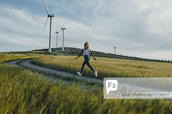 Young woman running on footpath amidst meadow
