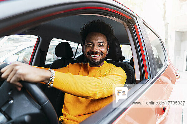 Smiling Afro man sitting on driver's seat