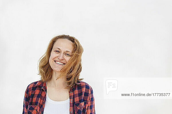 Happy woman wearing plaid shirt standing against white background