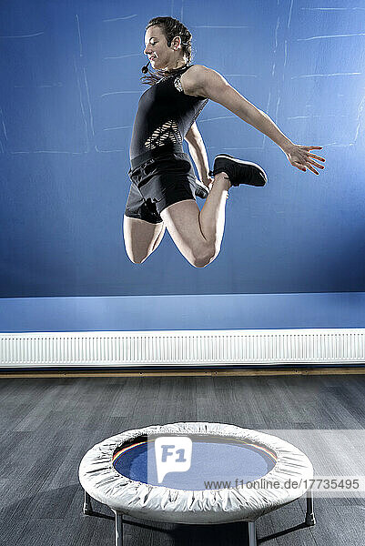 Young gymnast jumping on small trampoline