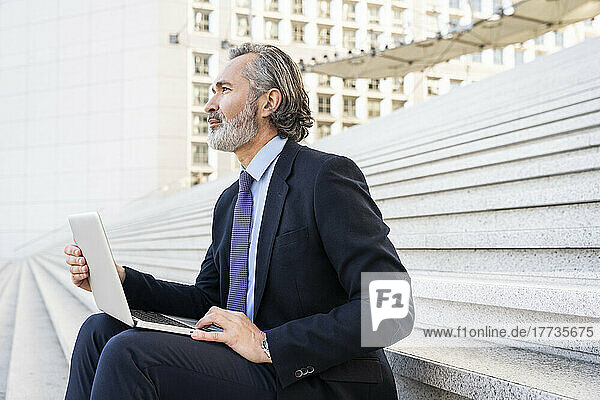 Businessman with laptop sitting on staircase