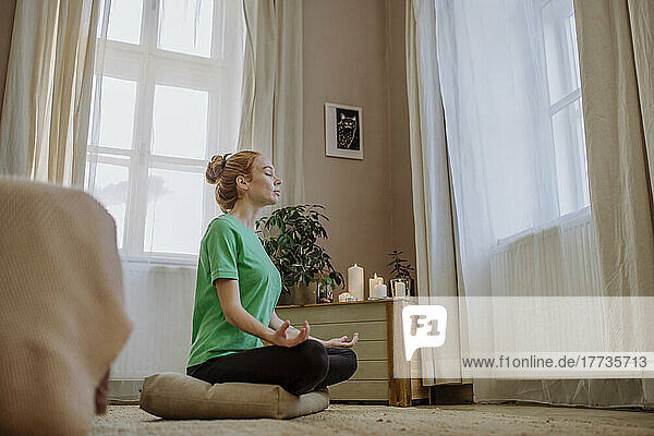 Woman with eyes closed practicing breathing exercise at home