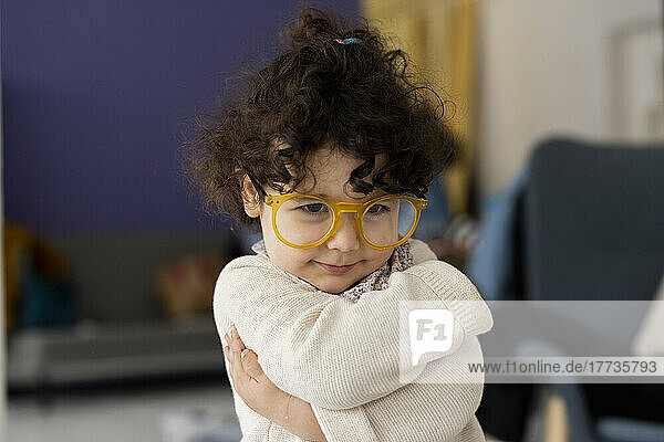 Niedliches kleines Mädchen mit übergroßer Brille  das sich selbst umarmt