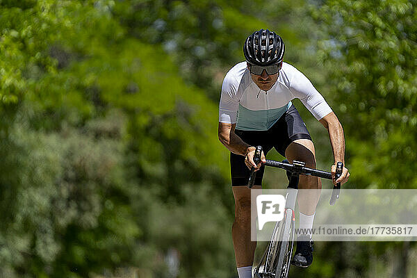 Dedicated mature athlete riding bicycle on sunny day