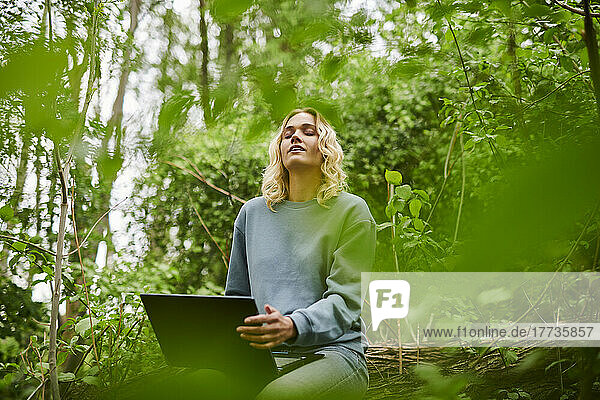 Young freelancer relaxing in nature and using laptop