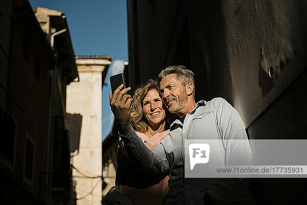 Mature couple taking selfie on mobile phone at sunny day