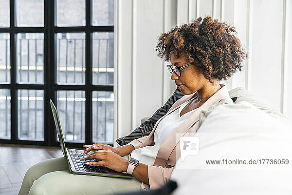 Young woman using laptop siting on sofa at workplace