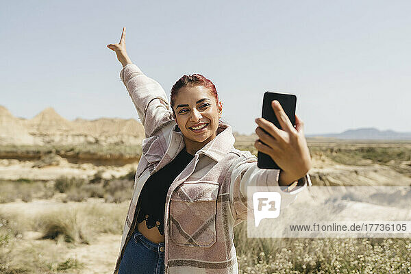 Glückliche Frau  die an einem sonnigen Tag ein Selfie mit dem Handy macht