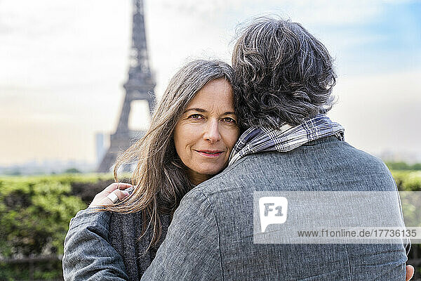 Lächelnde reife Frau umarmt Mann vor dem Eiffelturm  Paris  Frankreich