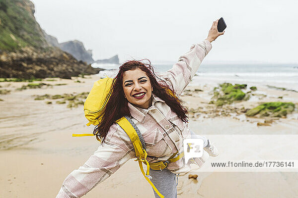 Smiling woman holding smart phone enjoying at beach