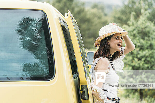 Glückliche junge Frau  die sich auf einen gelben Lieferwagen stützt
