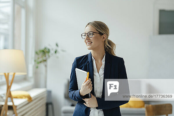 Smiling beautiful businesswoman holding tablet PC in office
