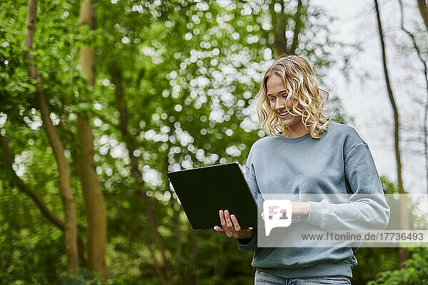 Happy freelancer working on laptop in forest