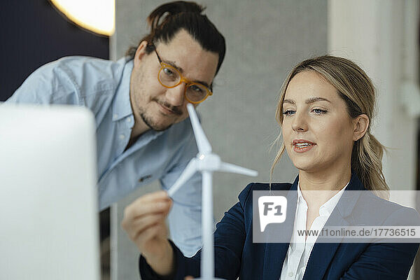 Engineer discussing with colleague over wind turbine model in office