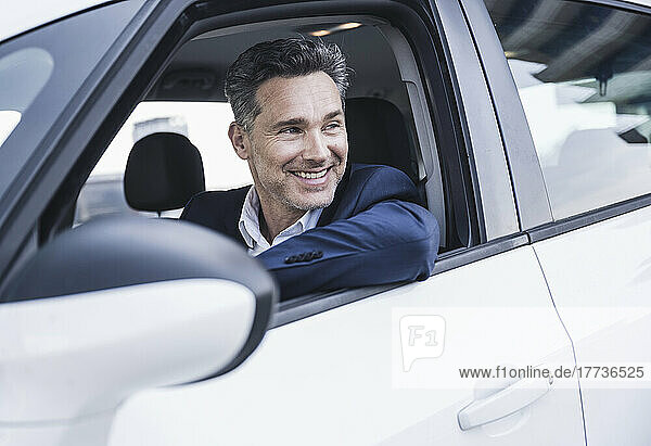 Smiling mature businessman sitting in car