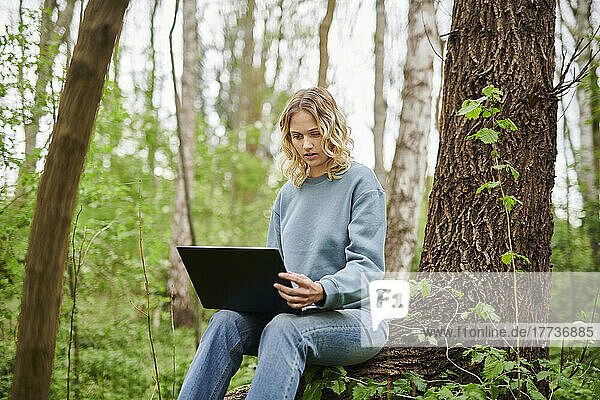 Shocked freelancer looking at laptop in forest