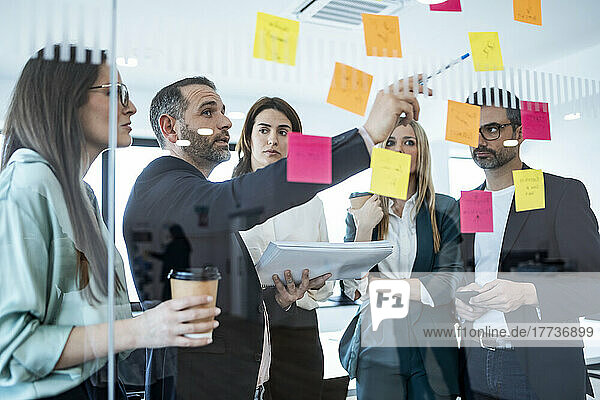 Businessman explaining colleagues over adhesive notes in meeting at office