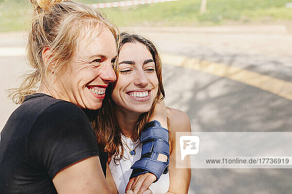 Happy woman embracing friend at skateboard park