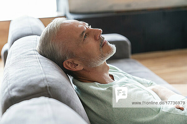 Mature man resting on sofa at home