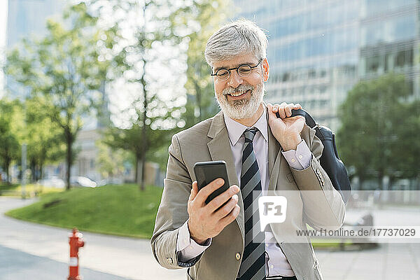Happy businessman wearing eyeglasses using smart phone