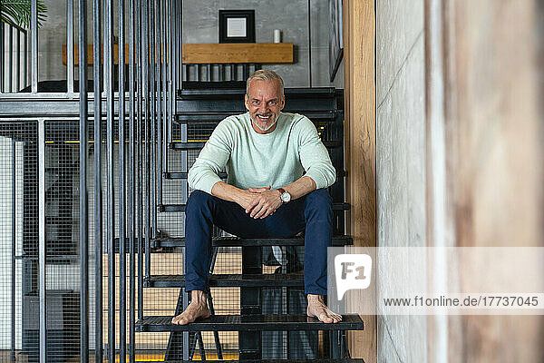 Happy man sitting on staircase at home